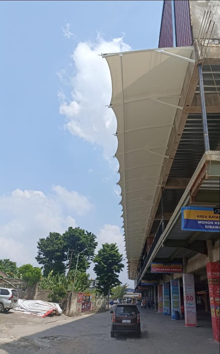 Kanopi membrane putih bersudut runcing di sisi bangunan tepi jalan